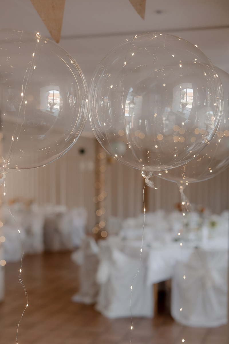 I bakgrunden syns vita dukade bord och i fokus är genomskinliga festliga ballonger